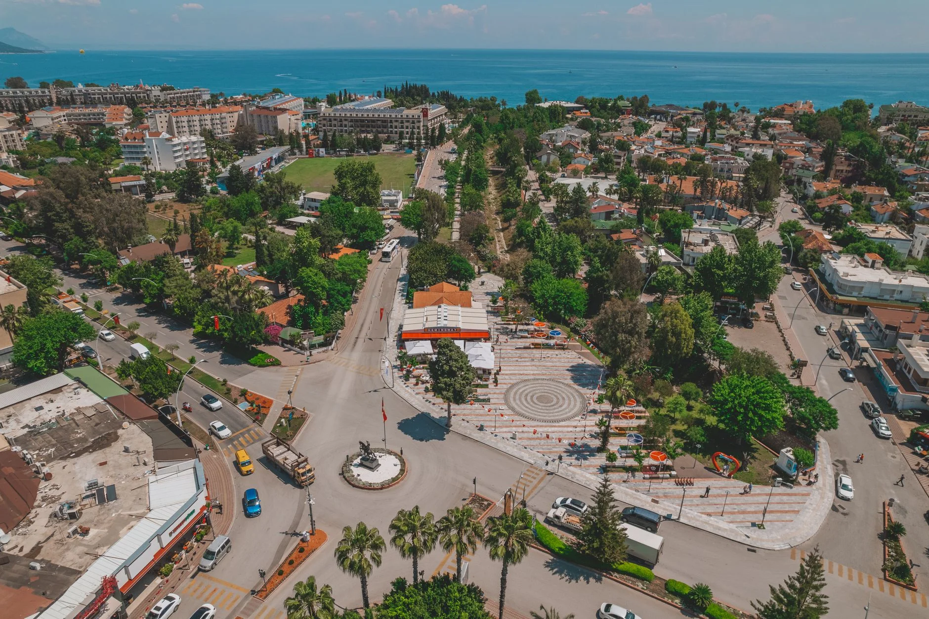 A vibrant aerial view showcasing Kemer cityscape with roads, greenery, and sea in Antalya, Türkiye.